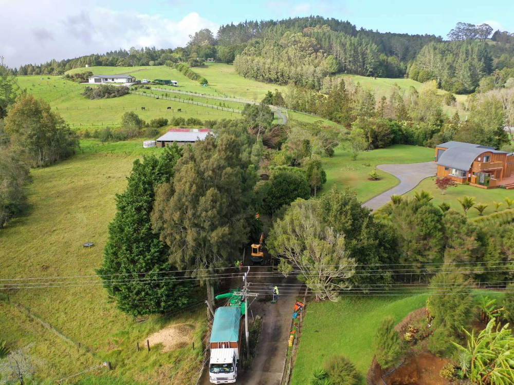 Aerial view of a rural property with the crew and truck working on trees beside a driveway and power lines
